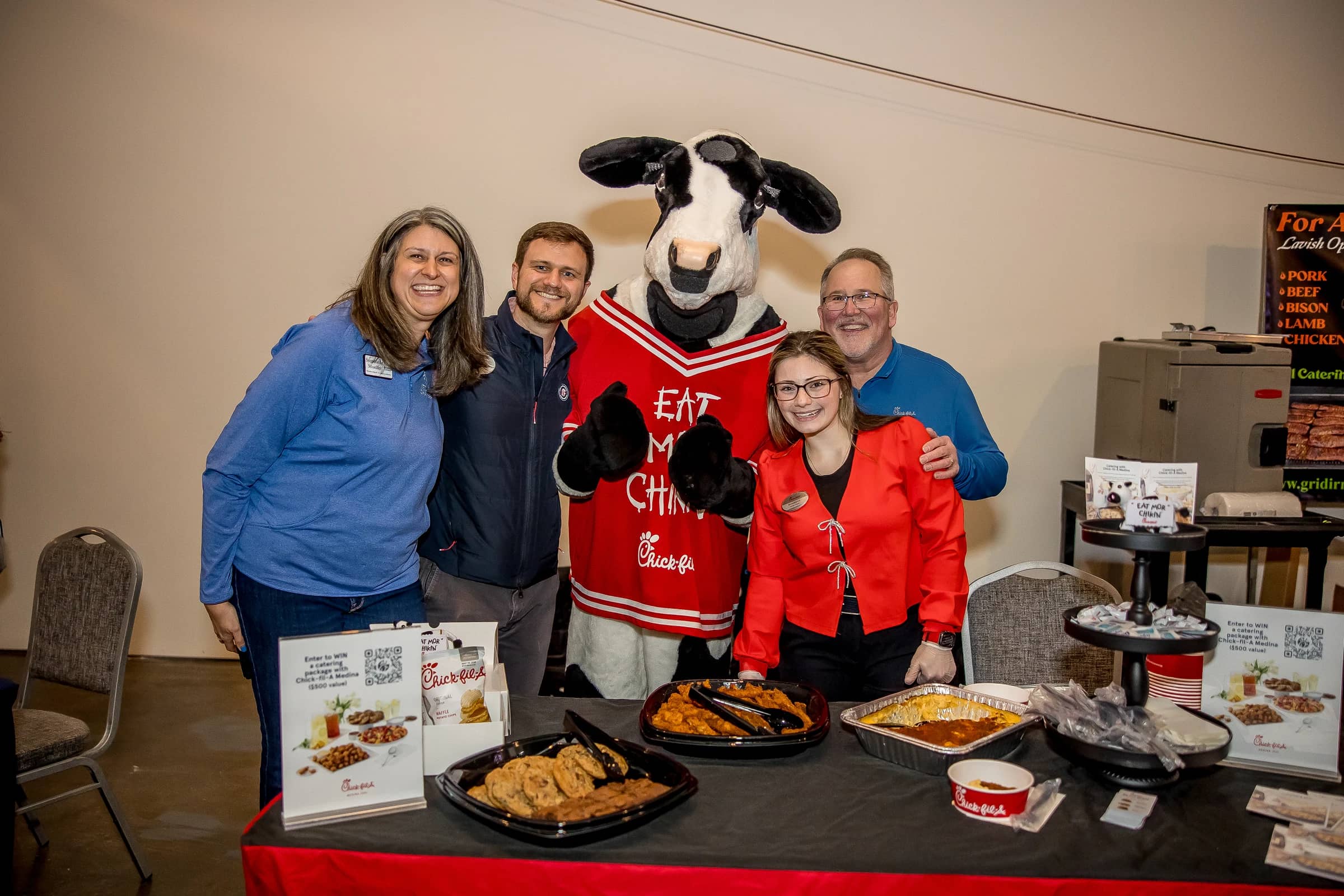 Attendees pose with the Chick-fil-A cow mascot at a Social Connect exhibitor table