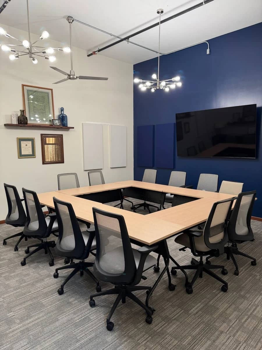 The Vault conference room with a square table, chandeliers and a navy accent wall